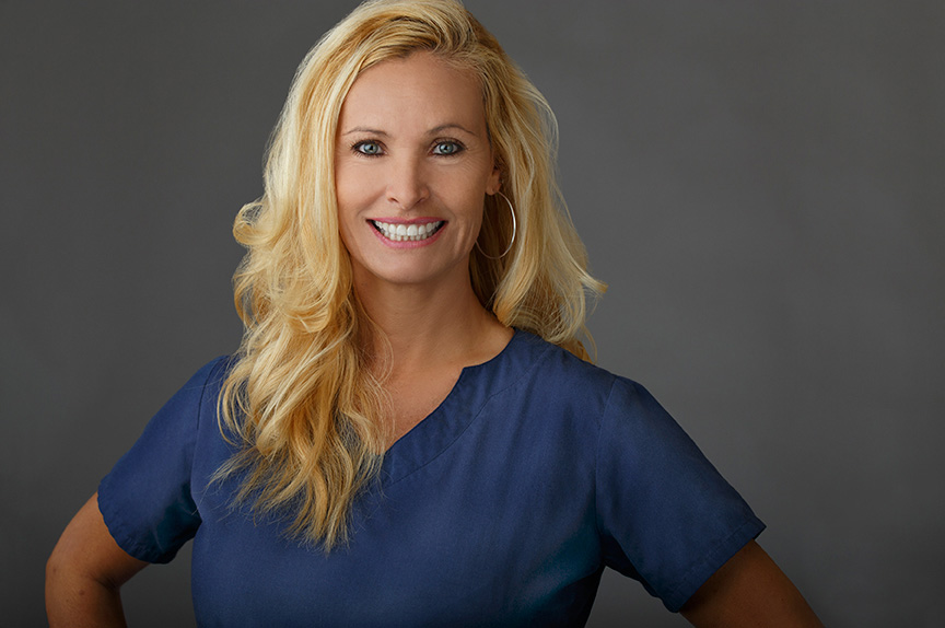 The image features a woman wearing a blue scrub top, posing with a confident smile against a neutral background.