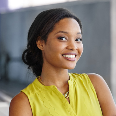 A woman with a radiant smile poses confidently against a backdrop, exuding positivity and warmth.