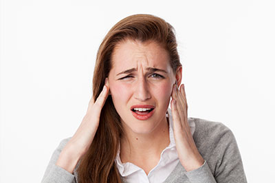 A woman with her hand on her head, appearing distressed, against a white background.
