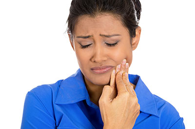 Woman with hand on face, looking downwards, possibly in pain or concern.